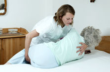 Grundpflege - Pflegerin hilft alter Dame ins Bett